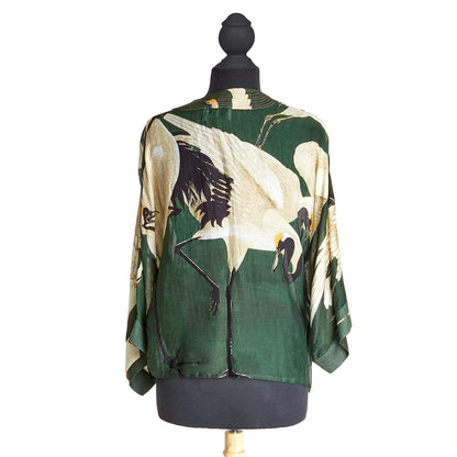 Heron Print Forest Green Short Kimono: Elegant heron design in white and black on a subtle forest green. Sustainable materials, wide sleeves, loose fit. Sizes available: S, M, L.