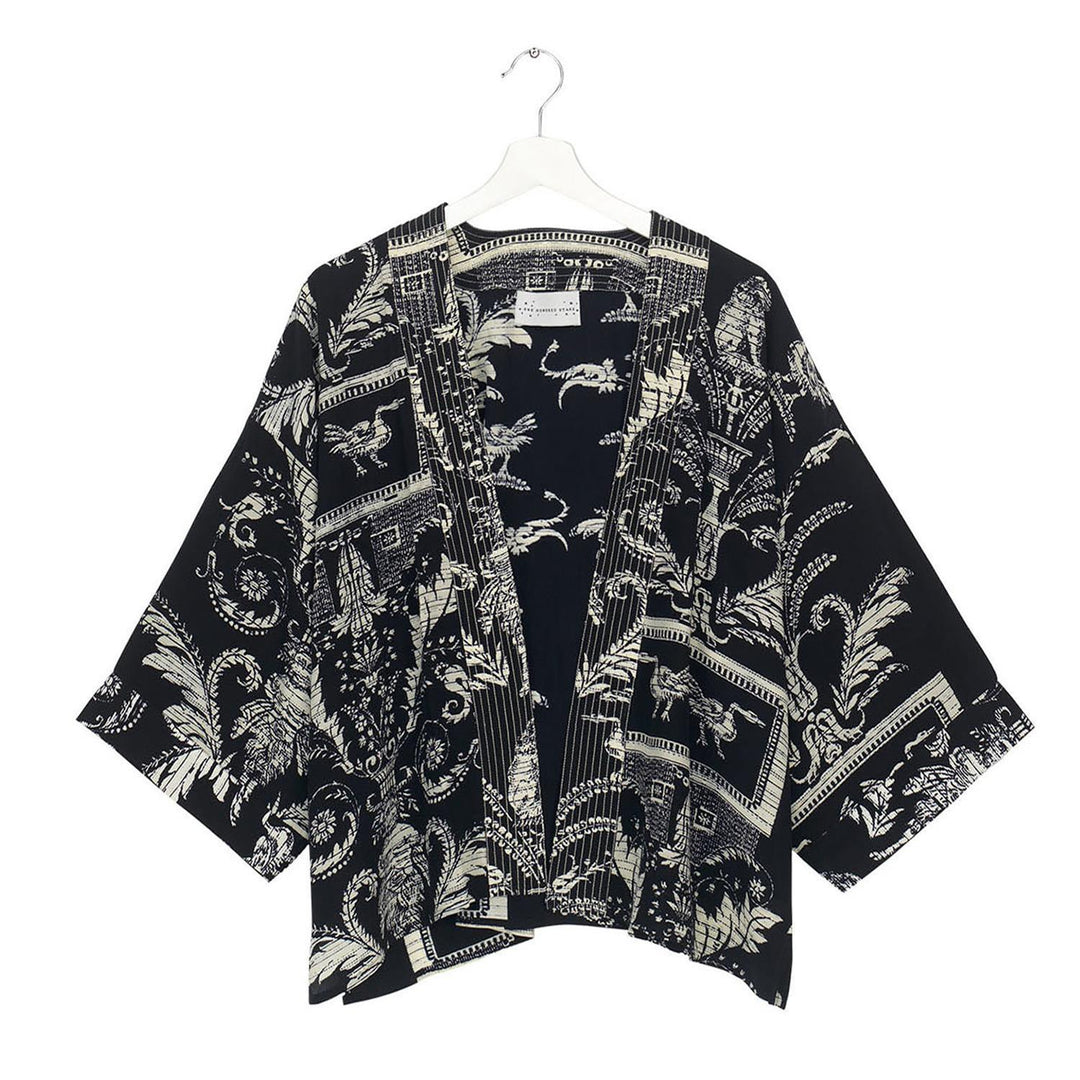 The Vintage Damask Black Short Kimono is made from crepe fabric with intricate white patterns of tropical leaves and decorative swirls. Available in sizes S, M, L, and XL.