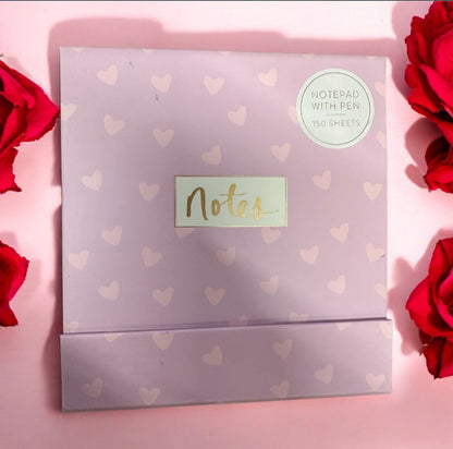Notepad with pen, heart design, “Notes” in gold, 150 sheets. Size info not provided. Sticker: “Notepad with pen, 150 sheets.”.