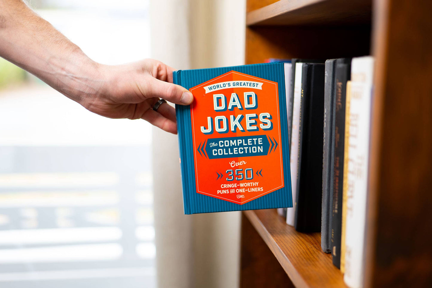 World’s Greatest Dad Jokes: The Complete Collection" book with blue and orange cover, 350+ jokes. Sizes available.