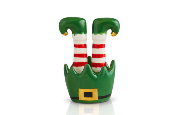 Nora Fleming Minis Christmas decoration featuring upturned elf legs in red and white striped stockings, green shoes with curled toes, and a green hat with a gold buckle. Available Sizes: One size.