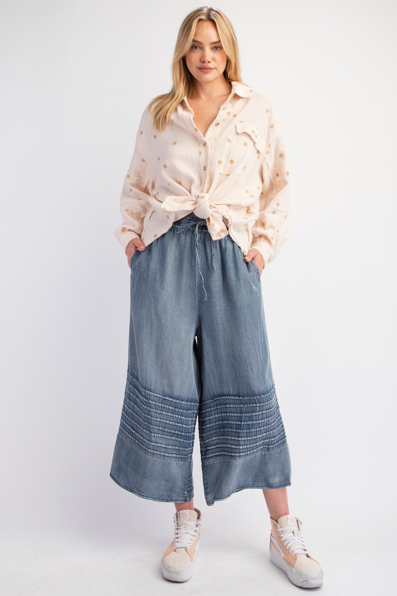 Light beige shirt with subtle patterns, tied at the waist. Mineral Washed Chambray Wide Leg Capri Pants with hem embroidery, sizes S/M/L. Paired with light-colored sneakers.