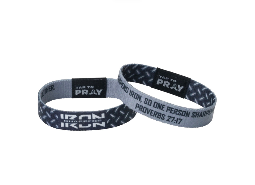 Two gray and black patterned elastic Tap To Pray™ Iron wristbands with diamond plate texture, featuring “Iron sharpens iron” and “Proverbs 27:17.”