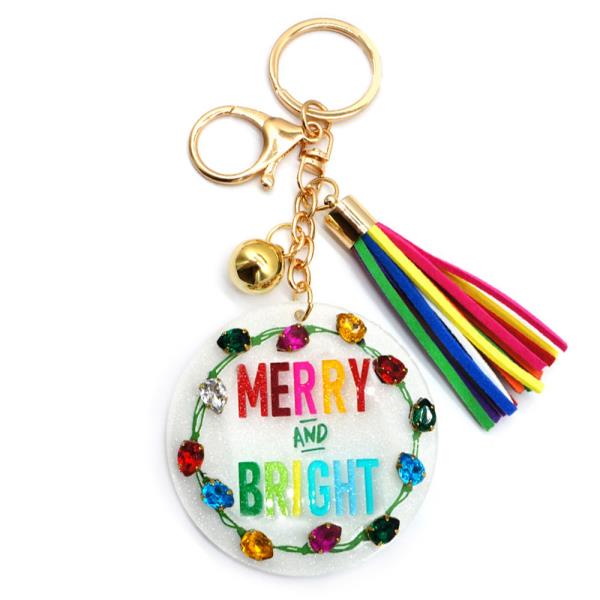 Christmas Spirit Keychain: Features "Merry and Bright" text, gold ring, small bell, multicolored tassel, and colorful gemstone-adorned round pendant available in one size.