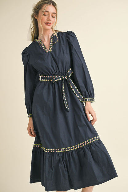 Kathy Embroidered Belt Midi Dress: navy, long sleeves, colorful trim on neckline, cuffs, waist, tiered skirt. Sizes XS-XL.