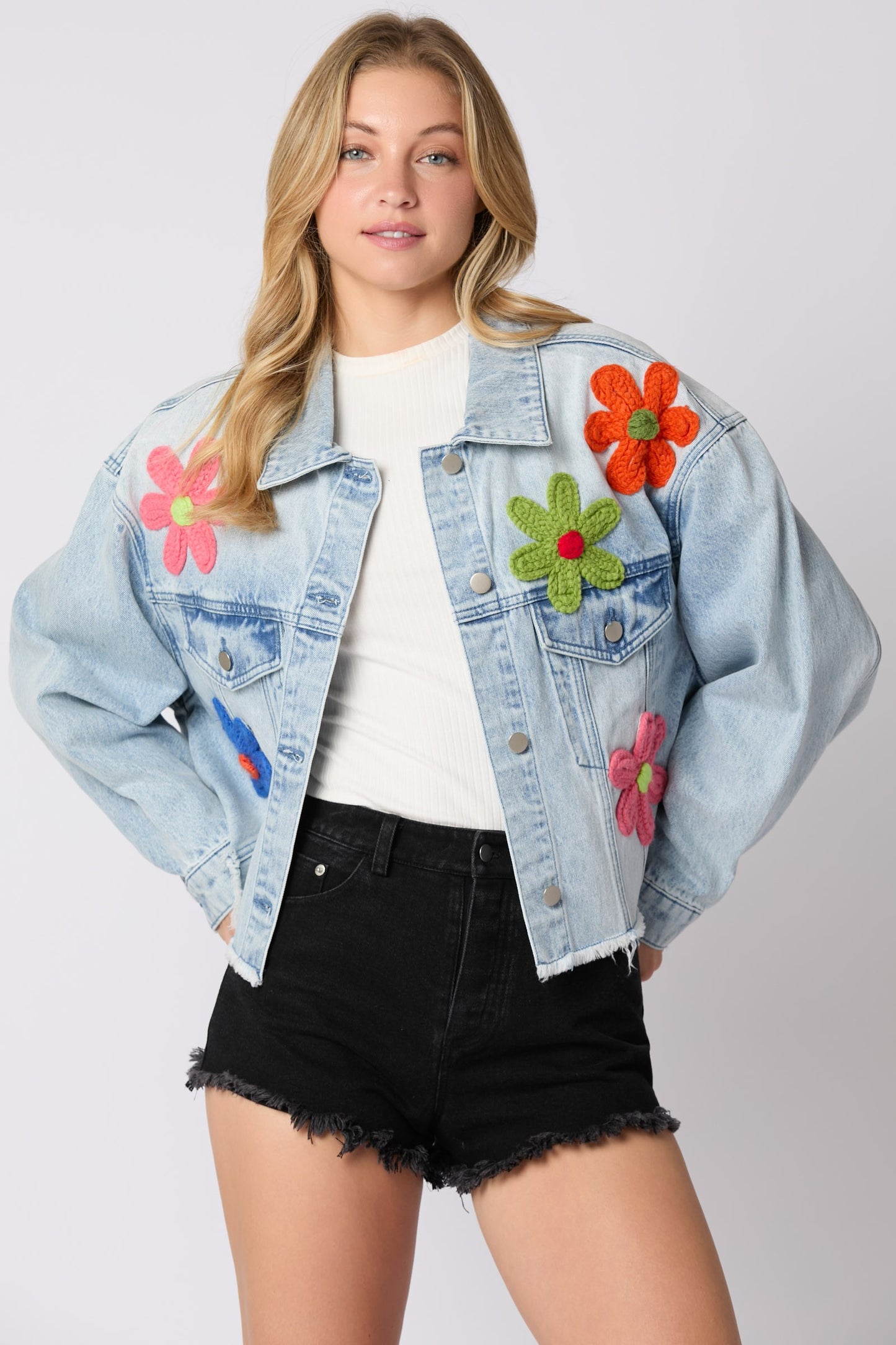 The Multi Color Flower Trim Oversized Denim Jacket features vibrant floral embroidery and an oversized fit. Available in sizes XS to XL.