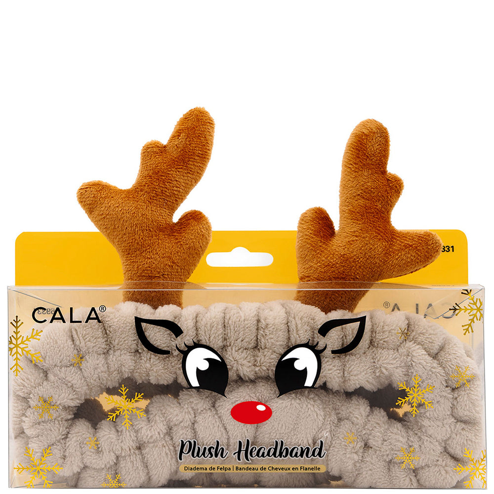 The Christmas Plush Spa Headband features soft fabric with fluffy brown reindeer antlers, a cartoon reindeer face, large eyes, and a red nose, accented by gold snowflake patterns. Available in one size.