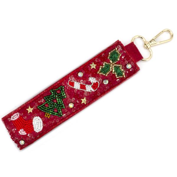 The Christmas Spirit Keychains feature red fabric with beaded holiday designs like Christmas trees, candy canes, holly, and stars. Attach to keys or bags with a gold clip. Available in one size.