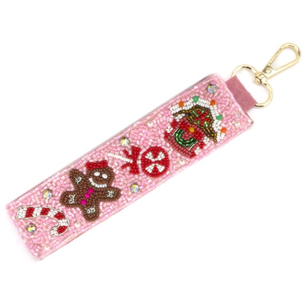 The Christmas Spirit Keychain is a pink beaded accessory featuring holiday ornaments like a gingerbread man, candy cane, peppermint, and holly. It has a gold clasp for easy attachment. Sizes available: One size.