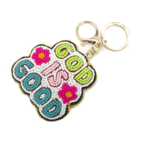 The God is Good Keychain features vibrant beaded embroidery with an inspiring message in green, pink, and blue. It includes delicate pink and white floral designs and a durable gold keyring. Available size: One Size.