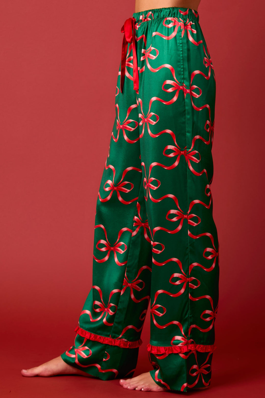 Satin Bow Prints Tie Front Ruffle Detailed Long Sleeve Pajama Set in green with a red ribbon print, red drawstring waist, and ruffled red hems. Available in various sizes.