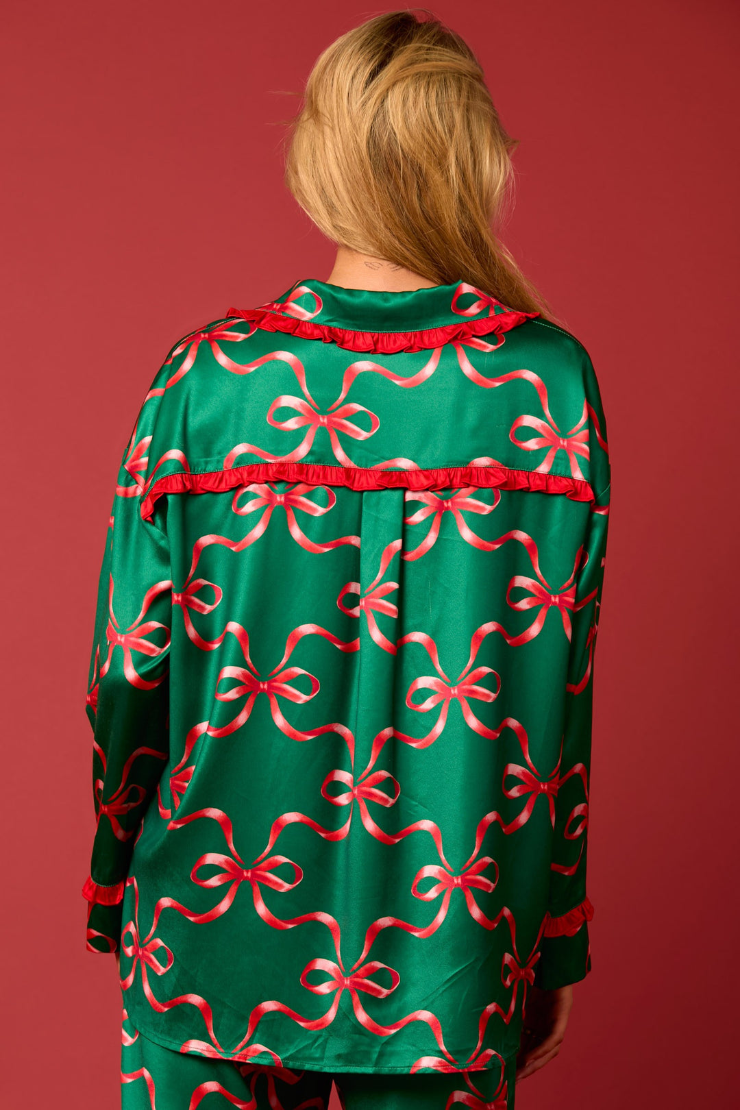 Green tie-front pajama set with red bow print and ruffle trim. Long sleeves. Available in all sizes.