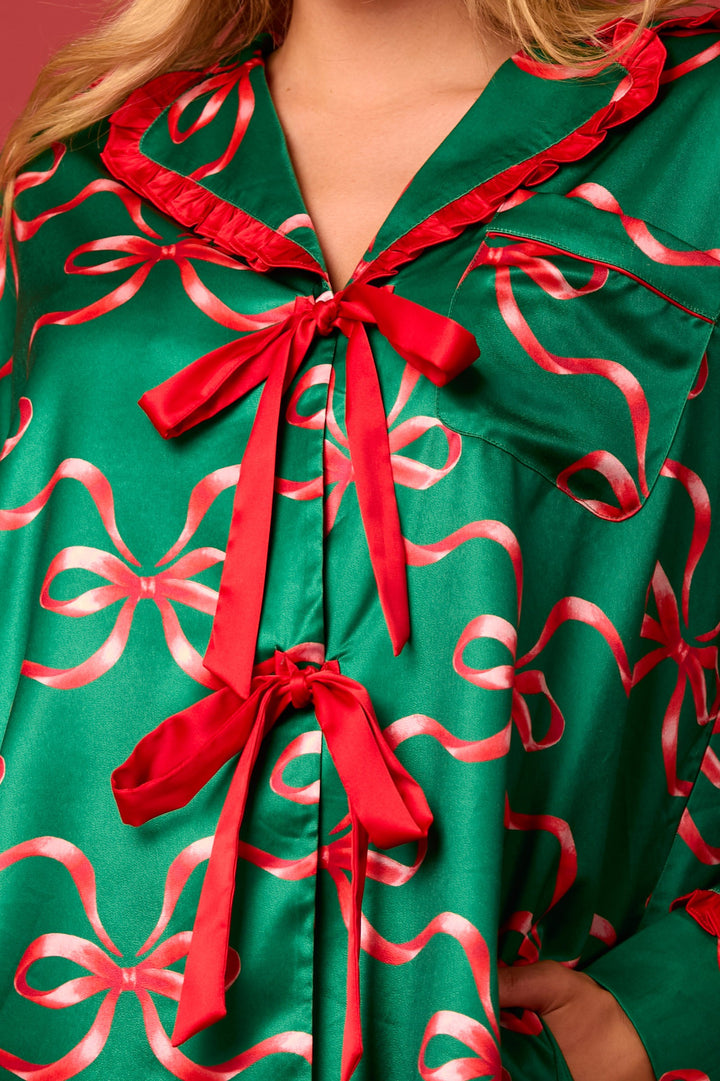 Green long-sleeve pajama top with red bow print, ruffled collar, and front ribbon ties. Sizes available.