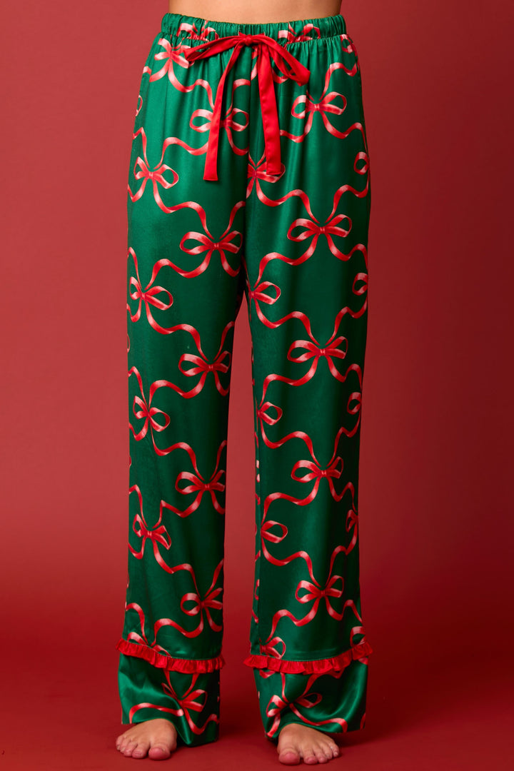 Green satin long sleeve pajama set with bow and ribbon prints, tie front, drawstring waist, and ruffled red hems.