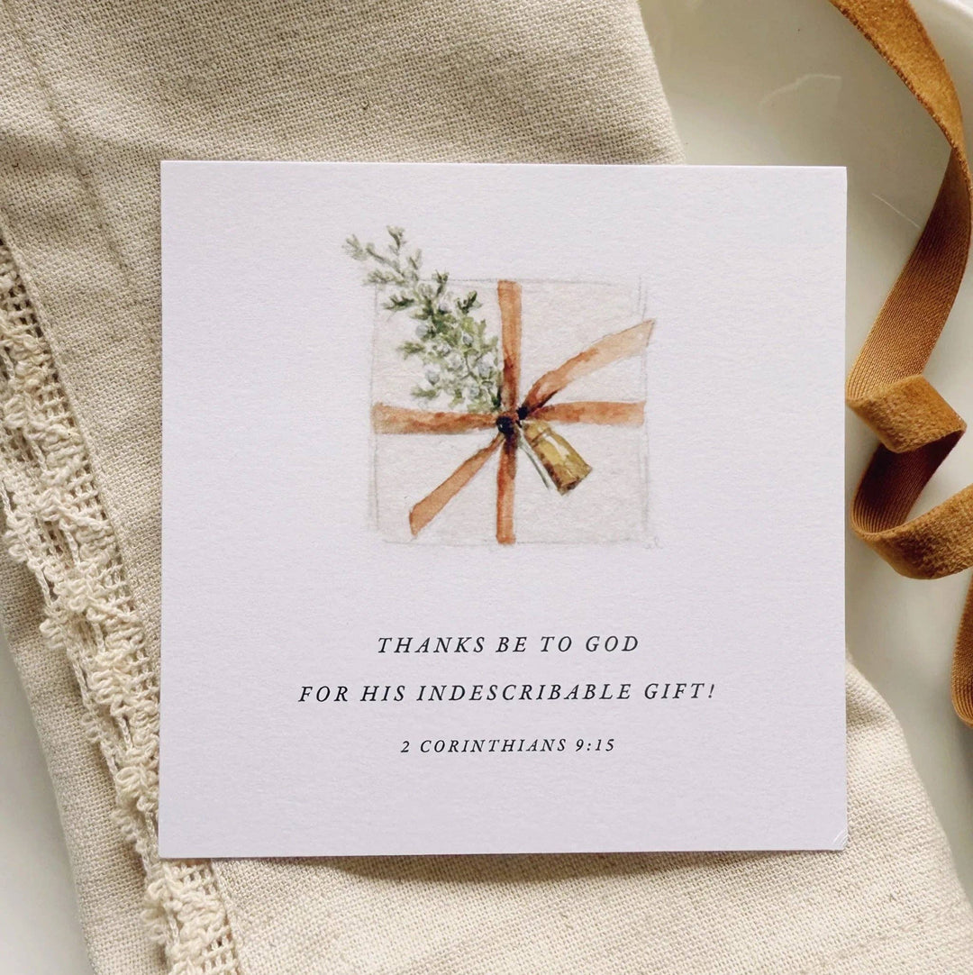 Christmas card with watercolor gift, brown ribbon, greenery, and 2 Corinthians 9:15. Available sizes: 4x6", 5x7".
