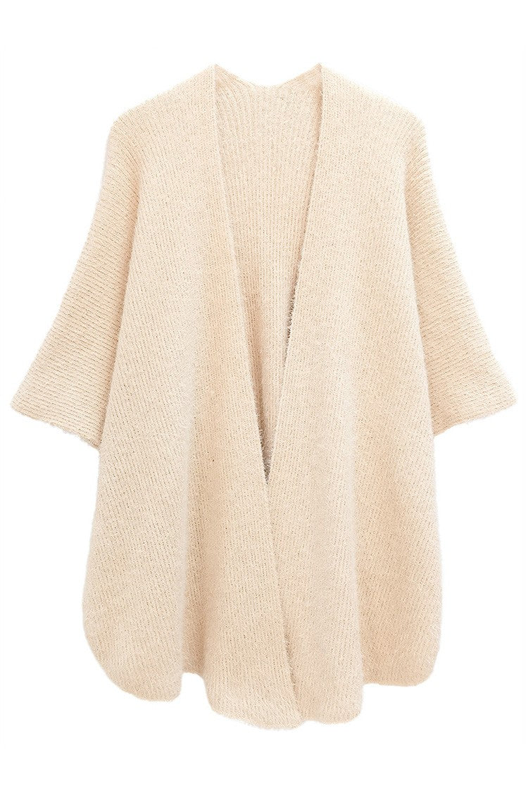 The Lurex Kimono Poncho is a beige oversized knitted cardigan with wide sleeves and an open front, designed for a casual and cozy look. Available in one size.