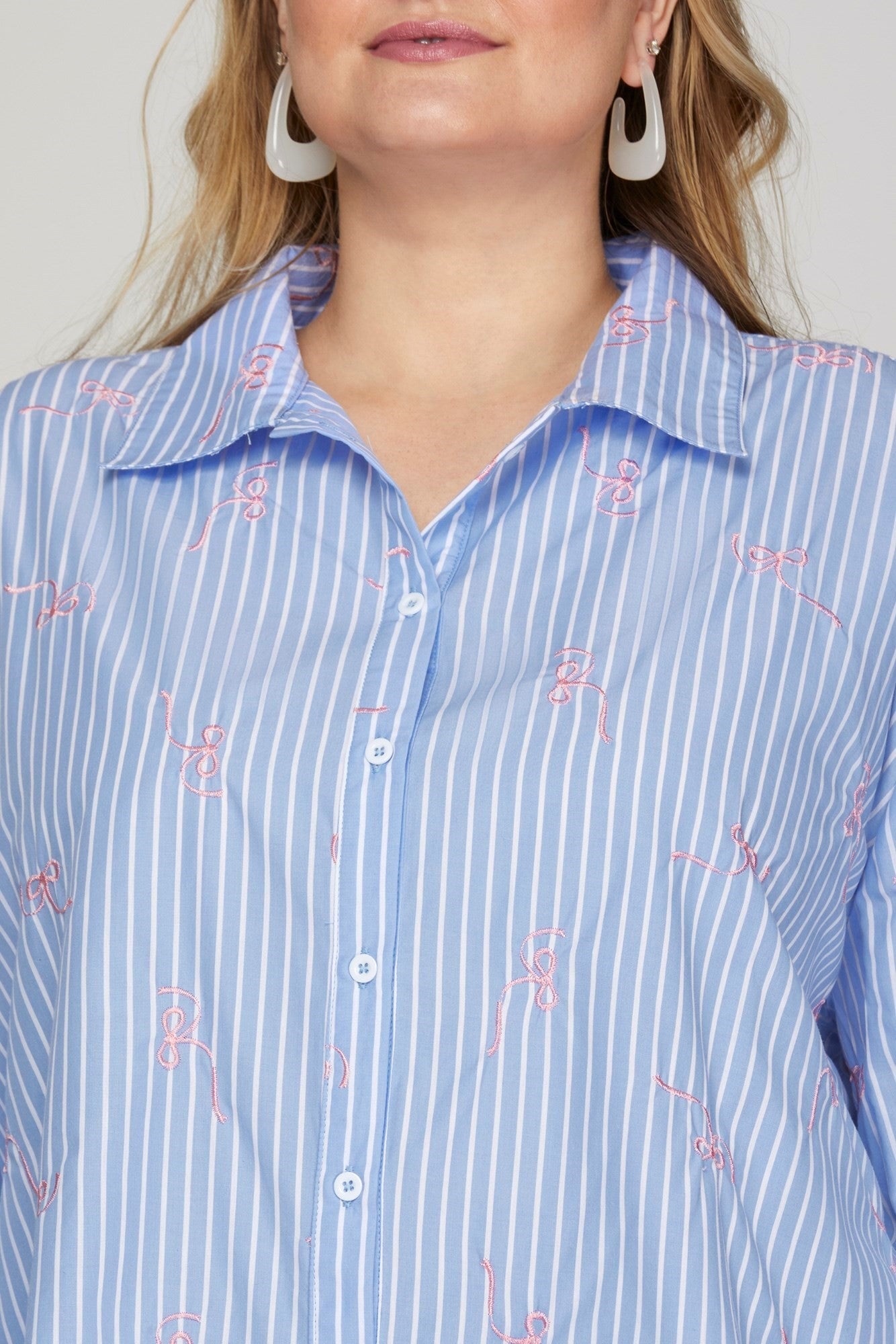 The Embroidered Bow Striped Button Down Top features blue and white stripes with pink embroidery, a relaxed fit, and a classic collar. Available sizes: XS, S, M, L, XL.