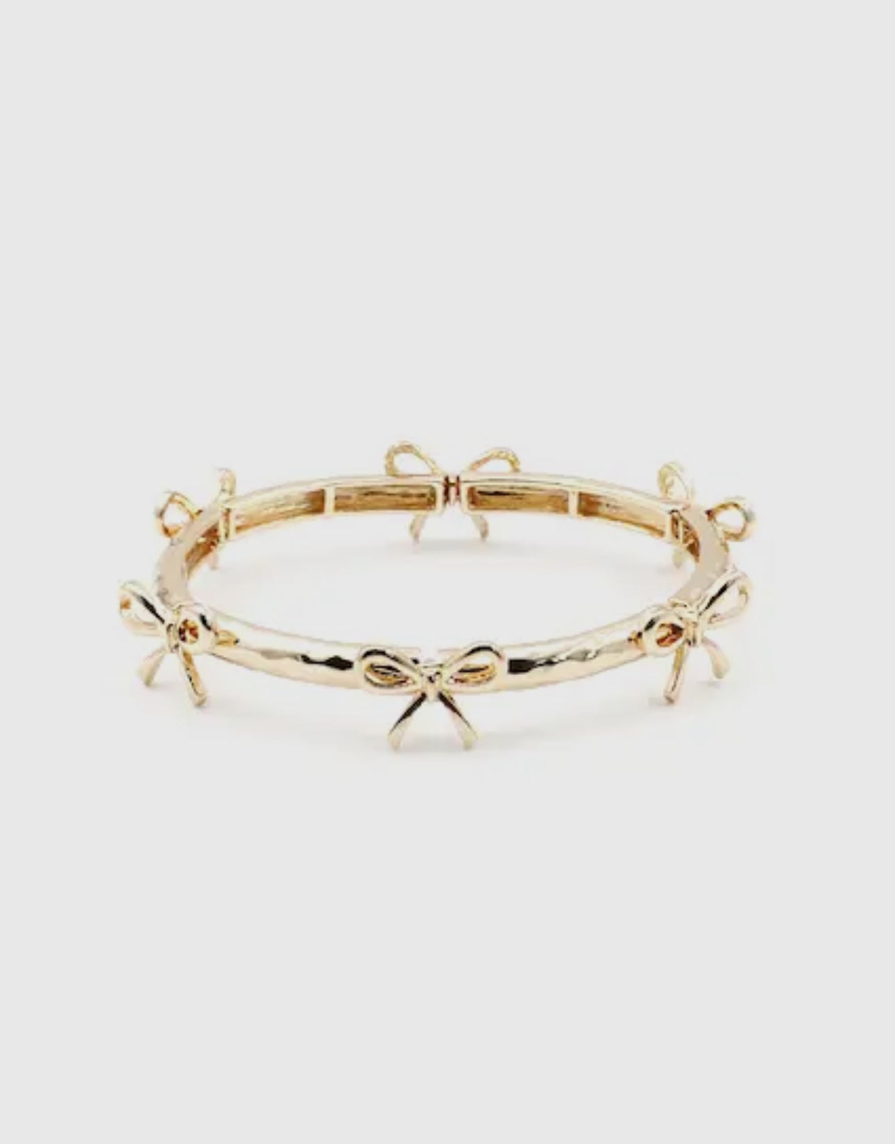 Gold stretch bracelet with evenly spaced small bow designs; available in one size fits most.