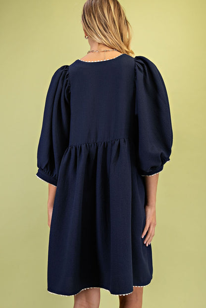 The Rosette Adorned V-Neck Mini Dress in navy blue features puff sleeves and a ric-rac trim. Available sizes: XS, S, M, L.