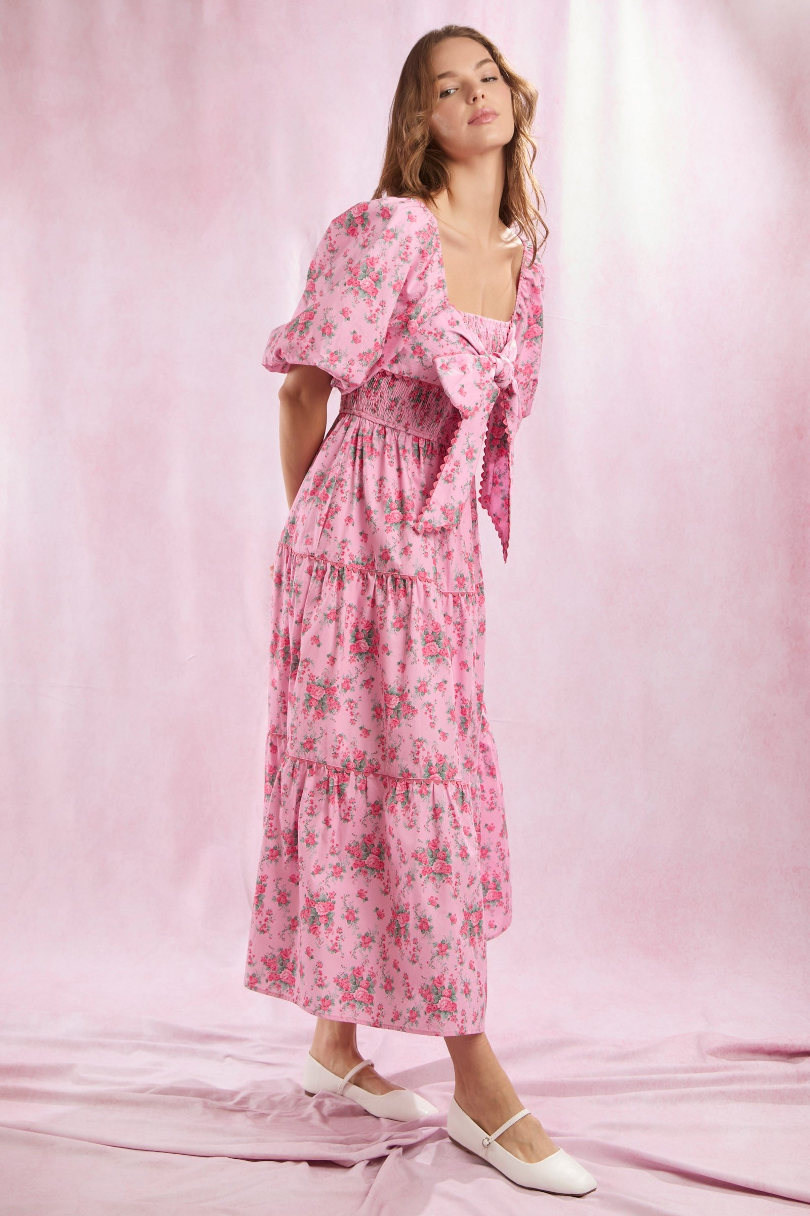 Bailey Floral Bow Front Maxi Dress: Pink floral print maxi dress with puff sleeves, bow front detail, and a tiered skirt. Available in sizes XS–XL.