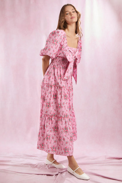 Bailey Floral Bow Front Maxi Dress: Pink floral print maxi dress with puff sleeves, bow front detail, and a tiered skirt. Available in sizes XS–XL.