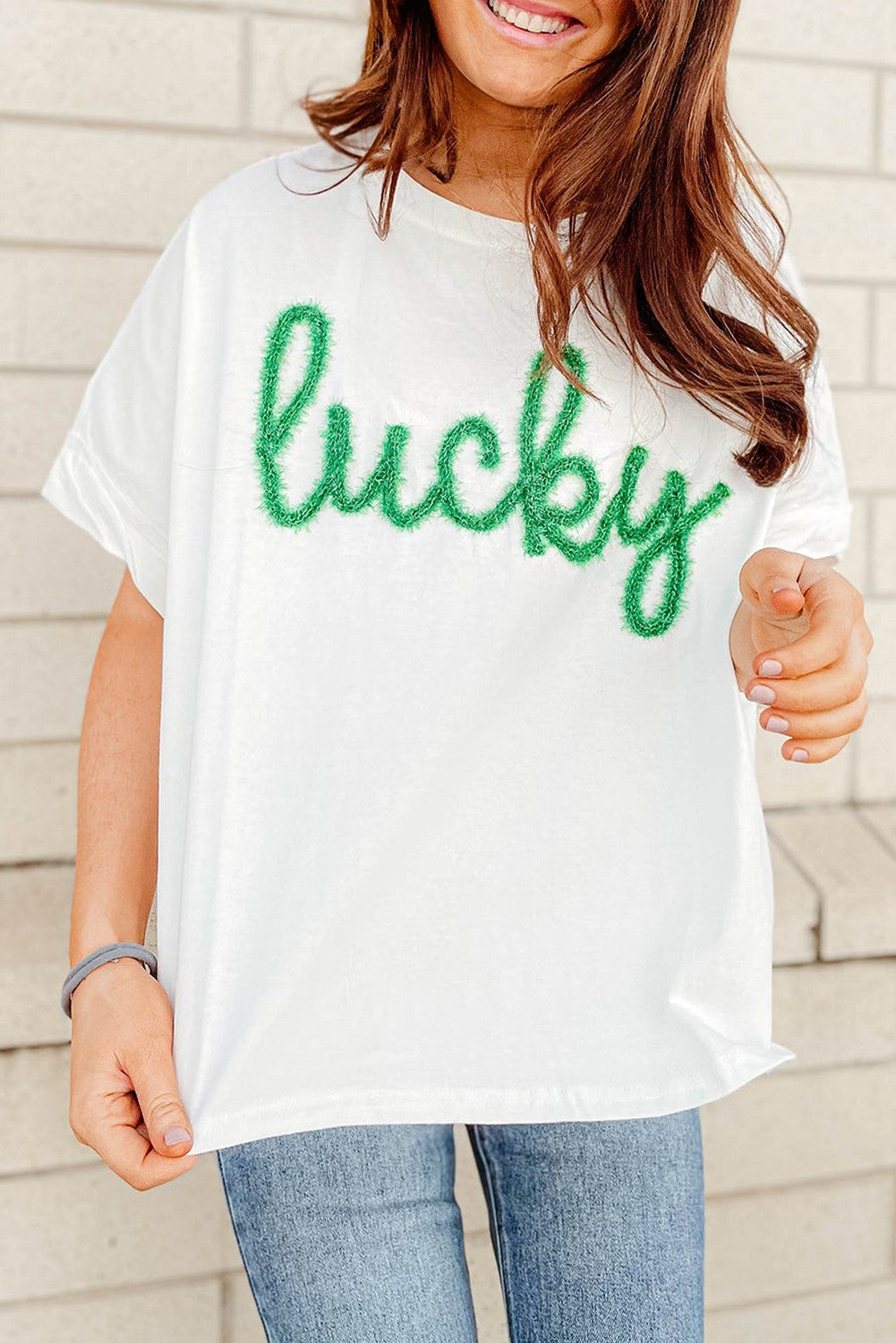 Fuzzy Corded Lucky Graphic St. Patrick's Day T-Shirt: White with "lucky" in green textured letters. Available sizes: S, M, L, XL.