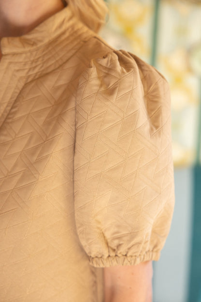 The Geometric Design Quilted Stitch Dress is beige with short, puffed sleeves and a subtle zigzag pattern. Available in sizes XS to XL.