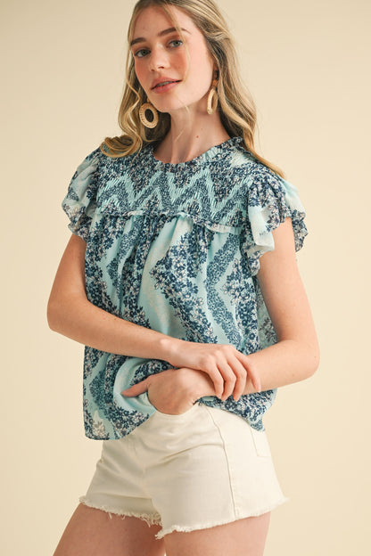 Teal Floral Smocked Yoke Ruffle Trim Top with floral pattern and ruffle detailing. Available in sizes XS-XL.