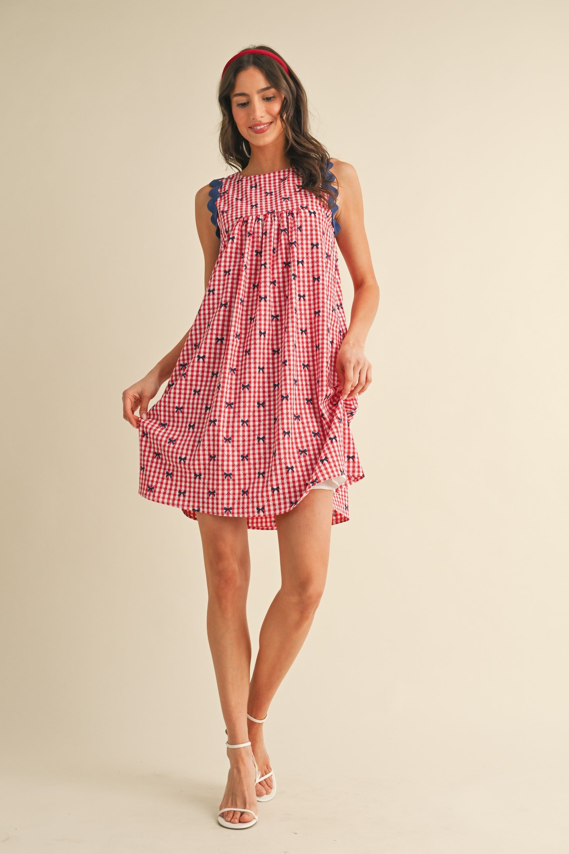 Miss Americana Bow Print Dress with red and white checks, blue ruffle details, and playful bow accents. Available in sizes XS-XL.