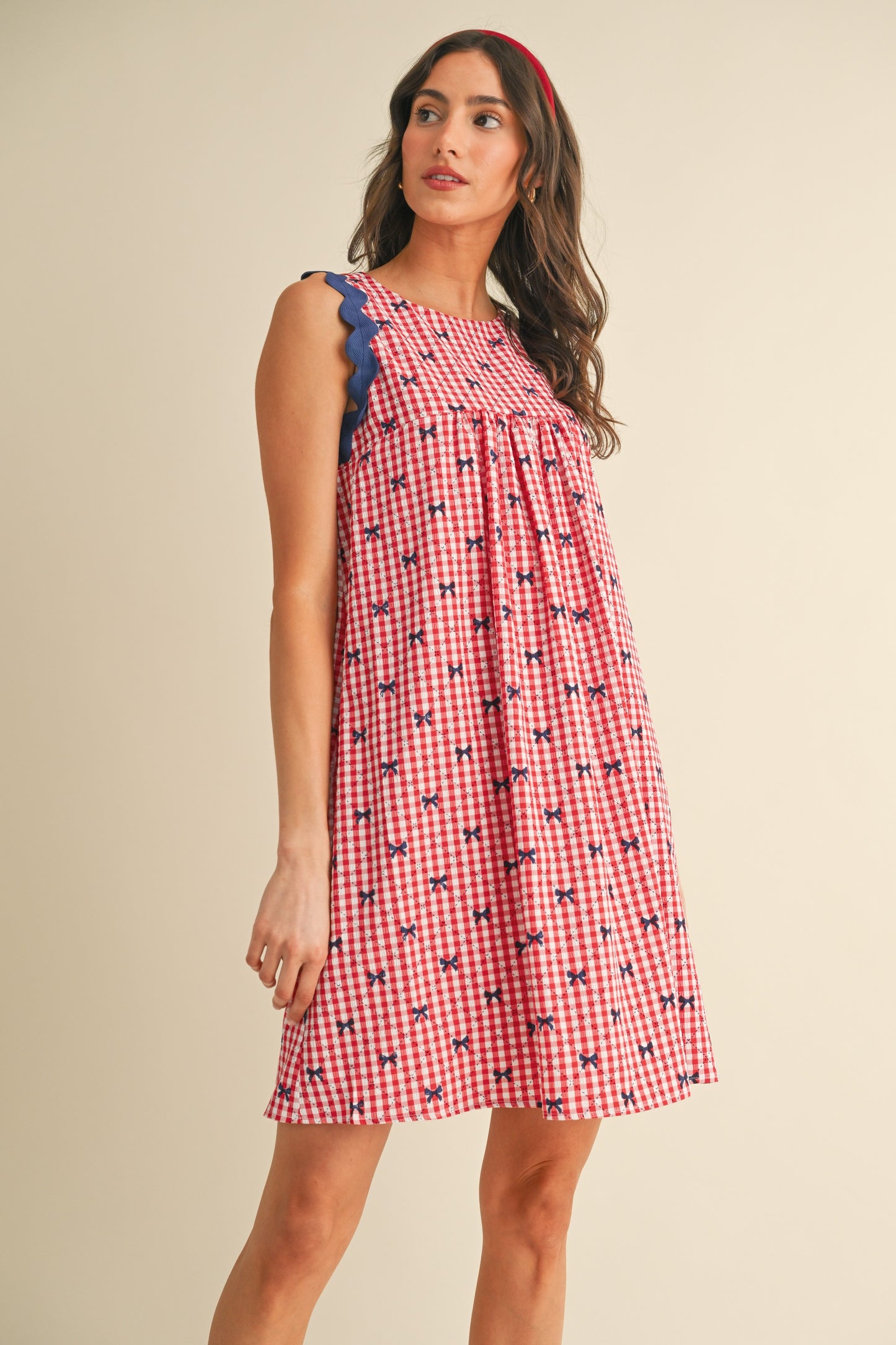 Miss Americana Bow Print Dress: Sleeveless, loose-fitting dress with red and white checkered print and blue bow accents. Available in sizes XS–XL.