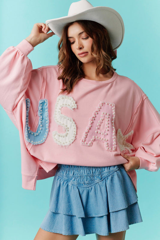 Pearls & Pastels USA Statement Top: White short-sleeve top with bold "USA" lettering. Available in sizes S, M, L, XL.