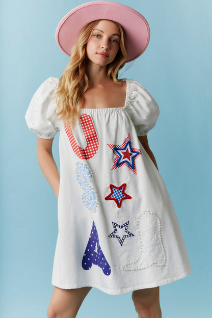 Star-Spangled Sweetheart Denim Dress with Pearl Details: Light blue denim dress featuring puffy sleeves and bold red, blue, and white appliqué stars, boot, “S,” and “U” designs. Sizes available: XS–XL.