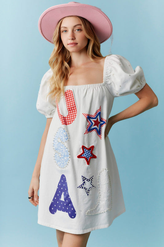 Star-Spangled Sweetheart Denim Dress with pearl details and bold red, white, and blue USA-themed accents. Available in sizes XS-XL. Perfect for Independence Day celebrations.