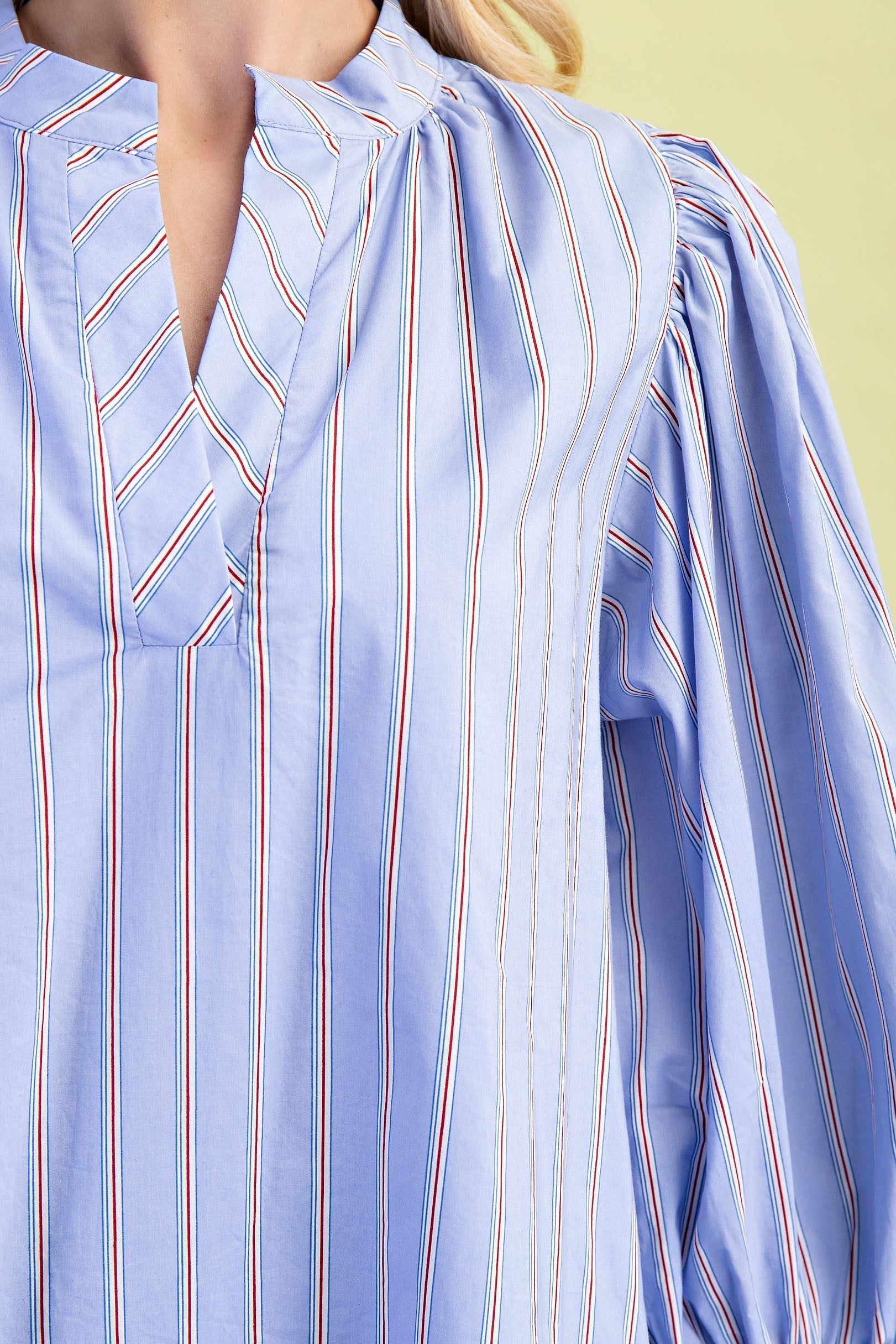 Leah Mixed Stripe Print Mini Dress with vertical red, white, and navy stripes. Features V-neckline with pleated details and long balloon sleeves. Available in sizes XS–XL.