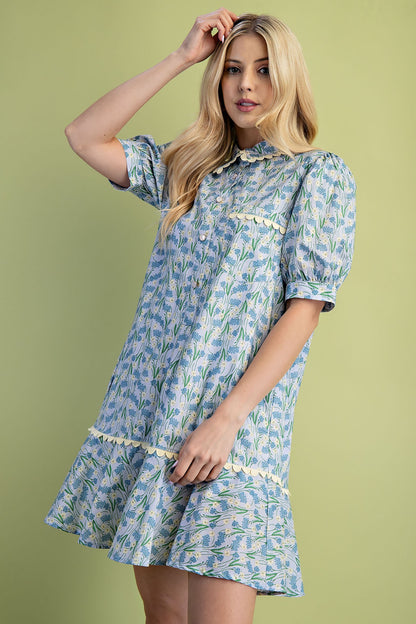 Mia Floral Print Mini Dress: 100% cotton, light blue and green floral pattern, puff sleeves, tiered skirt, scalloped trim. Available in sizes XS–XL.