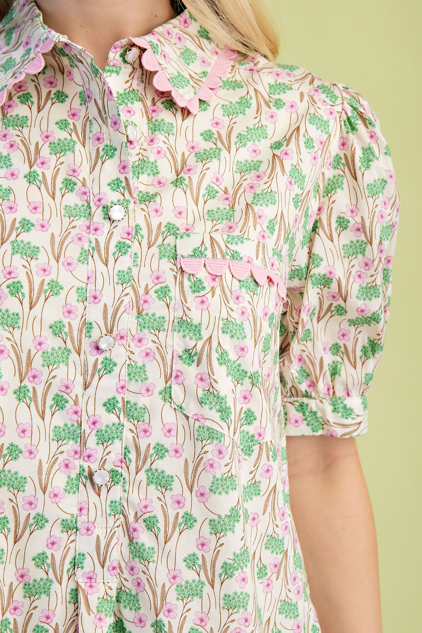 Mia Floral Print Mini Dress in pink and green floral pattern with scalloped collar, puffed short sleeves, decorative pink trim on collar, pocket, and sleeve edges. Made from 100% cotton lightweight fabric. Available in sizes XS–XL.