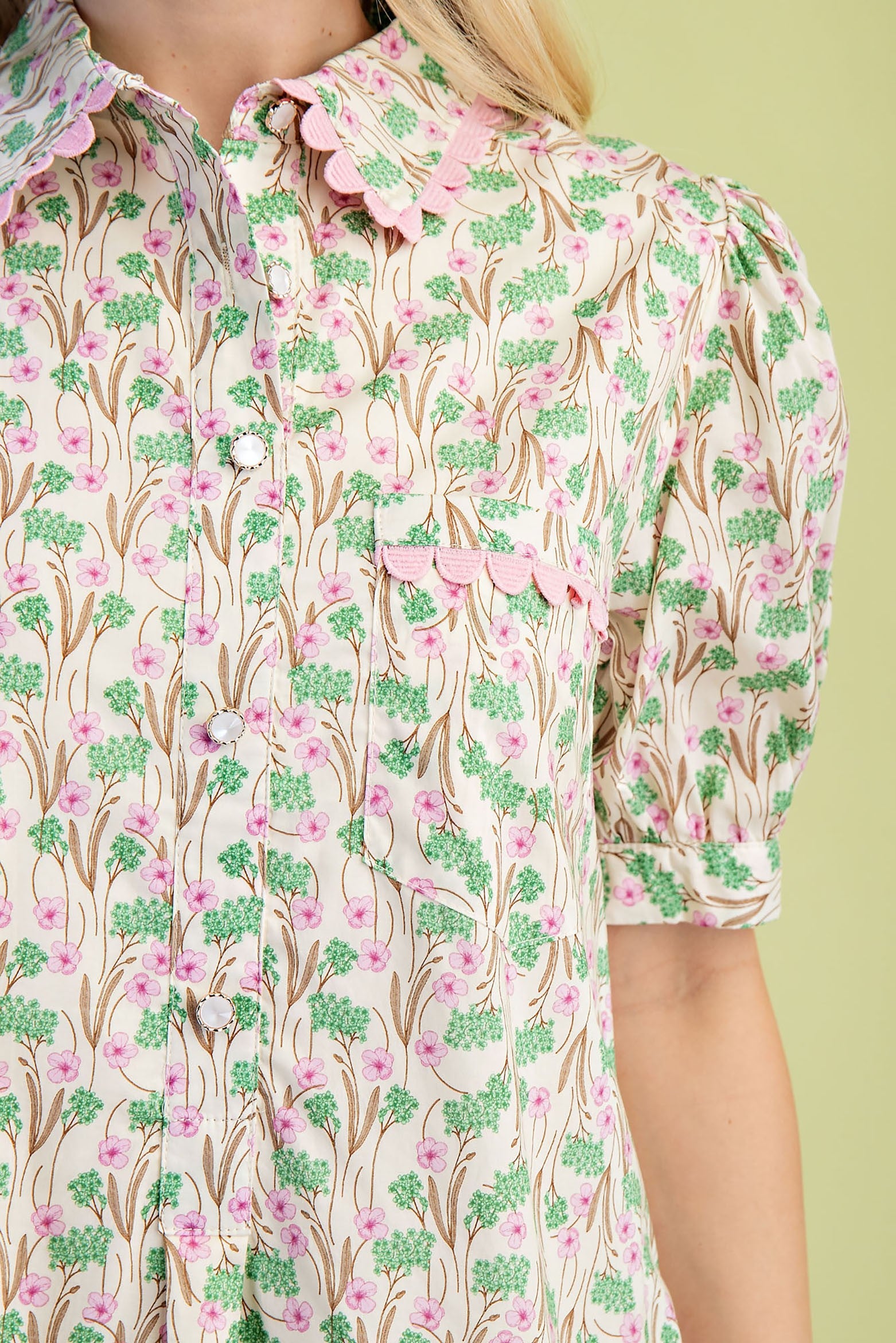 Mia Floral Print Mini Dress in pink and green floral pattern with scalloped collar, puffed short sleeves, decorative pink trim on collar, pocket, and sleeve edges. Made from 100% cotton lightweight fabric. Available in sizes XS–XL.