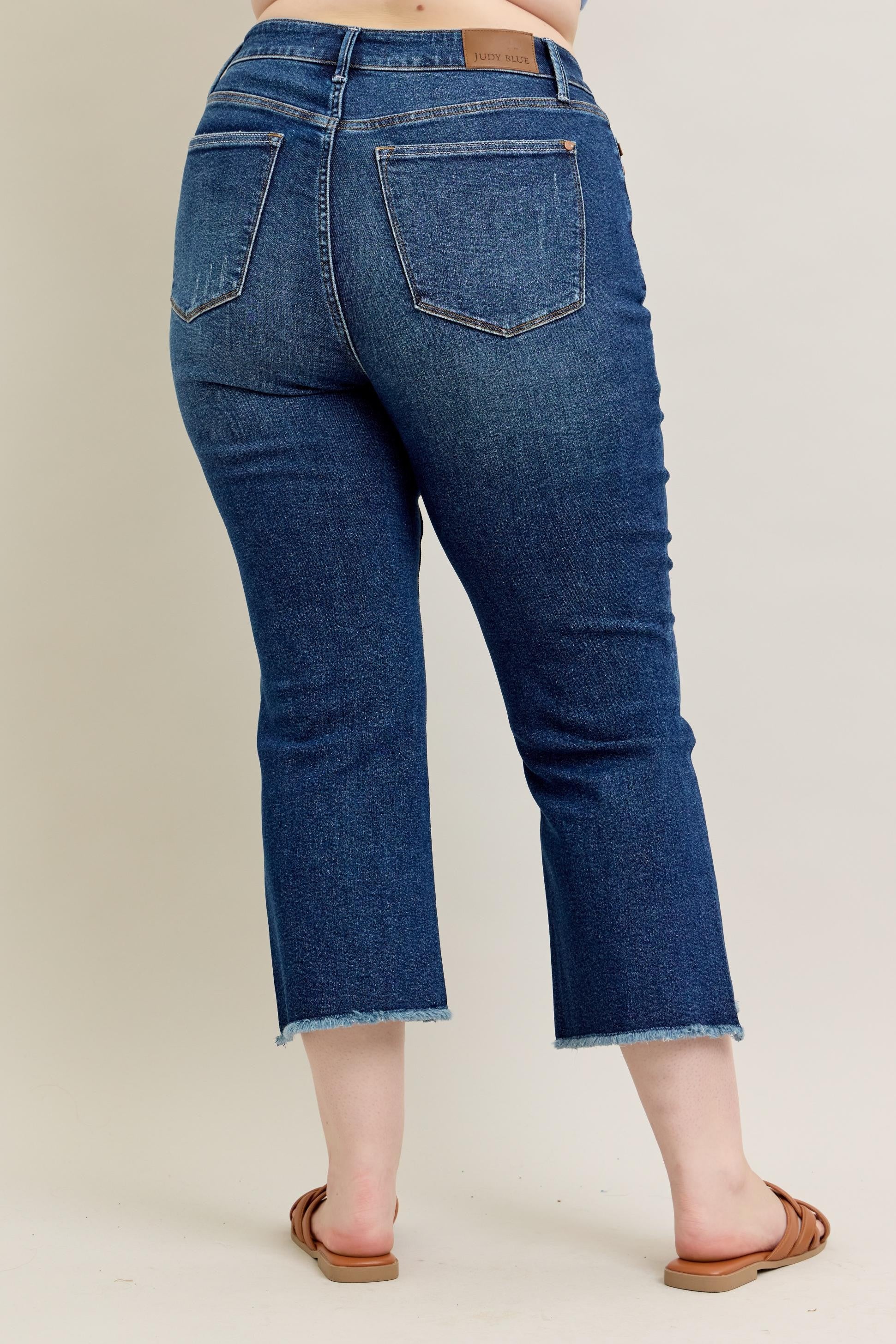 Judy Blue HW Dark Wash Kick Flare Jeans with frayed hems and brown leather patch on back waistband. Available in sizes 0-20W.
