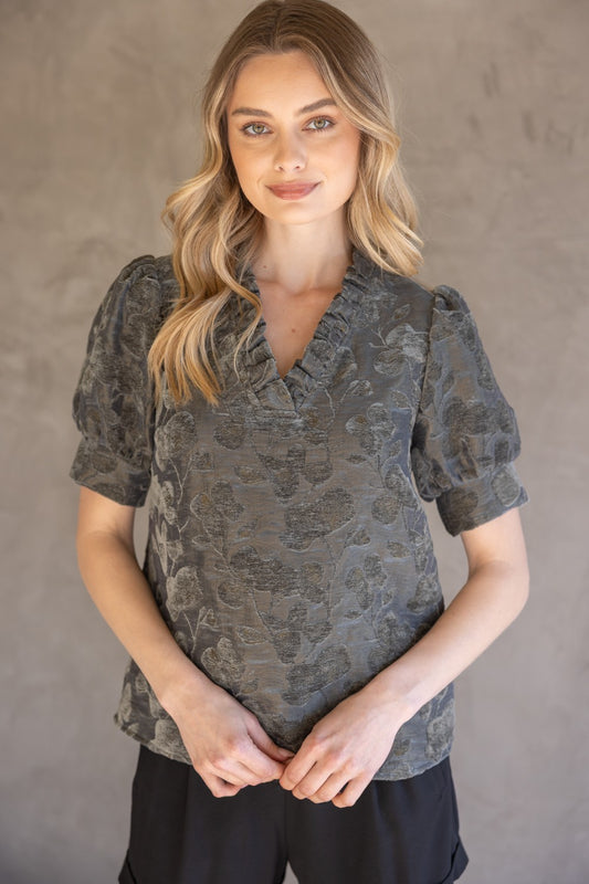Charcoal Ruffled V-Neck Textured Velvet Top, available in sizes XS–XL. Features ruffle details and a velvet texture.