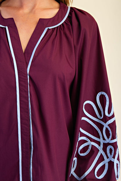 Maroon blouse with blue piping and sleeve embroidery; elegant style. Available in sizes XS–XL.