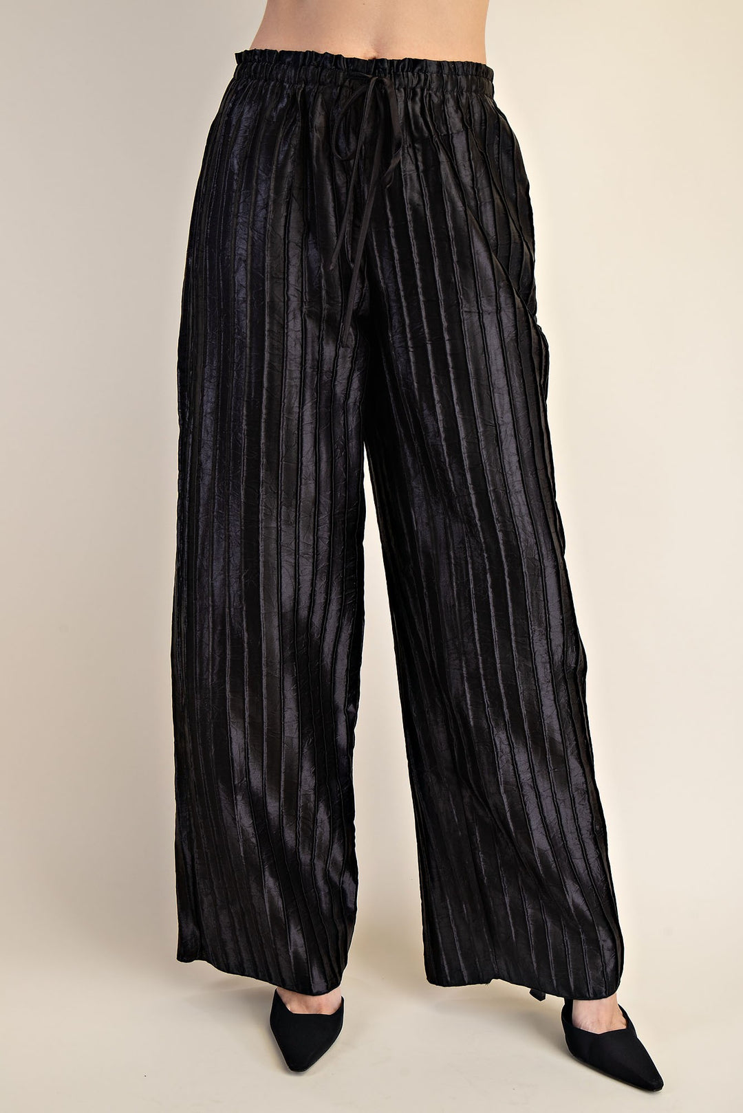 Black, high-waisted flowy pants with drawstring, vertical pleats, wide legs; available in sizes XS-XL.