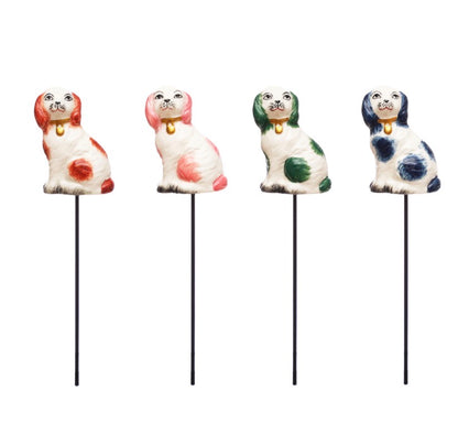 Set of four stoneware dog shape plant stakes with red, pink, green, and blue markings and small gold collars. Available in one size.