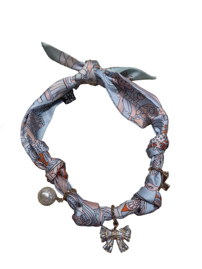 Pastel-patterned silk bracelet with knot, pearl charm, and rhinestone bow. Available in S, M, L. Water resistant.