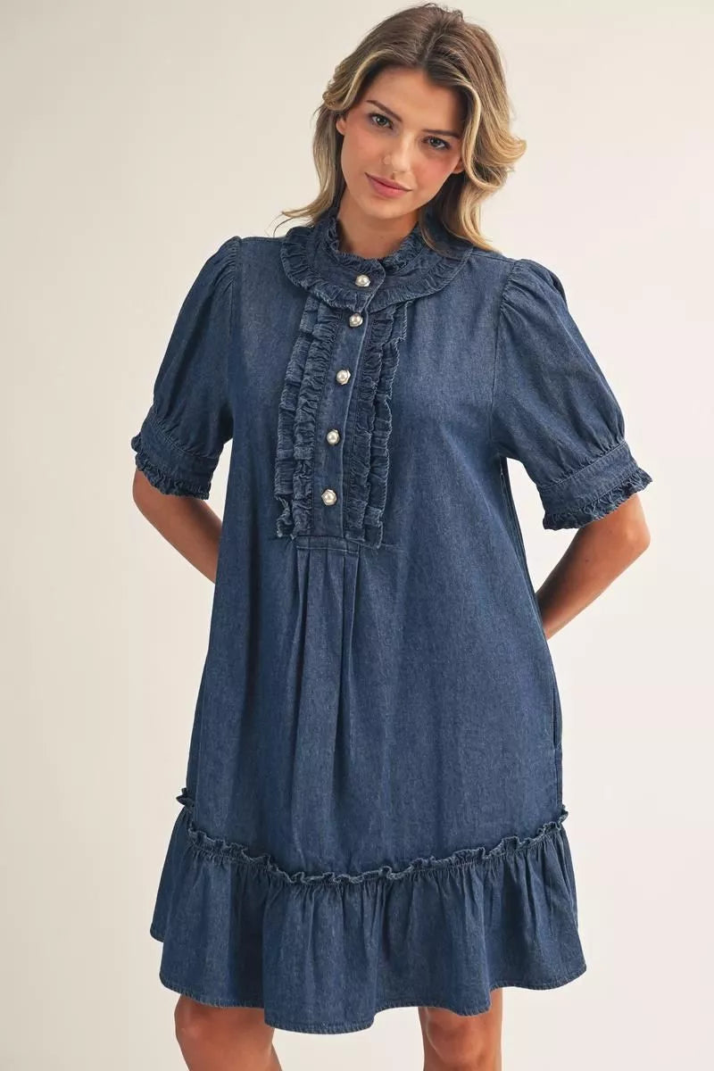 Blue Darcy Ruffle Denim Dress with short puff sleeves, ruffled collar and placket, pearl-style buttons, and ruffled hem in a button-front style. Sizes available.