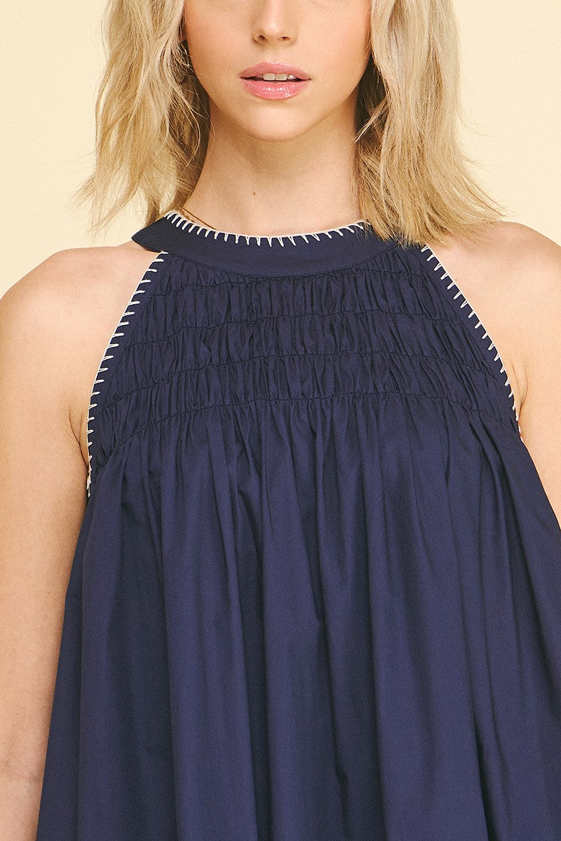 Navy Halter Neck A-line Dress: sleeveless navy cotton, white stitching, smocked neckline/armholes. Sizes XS-XL.