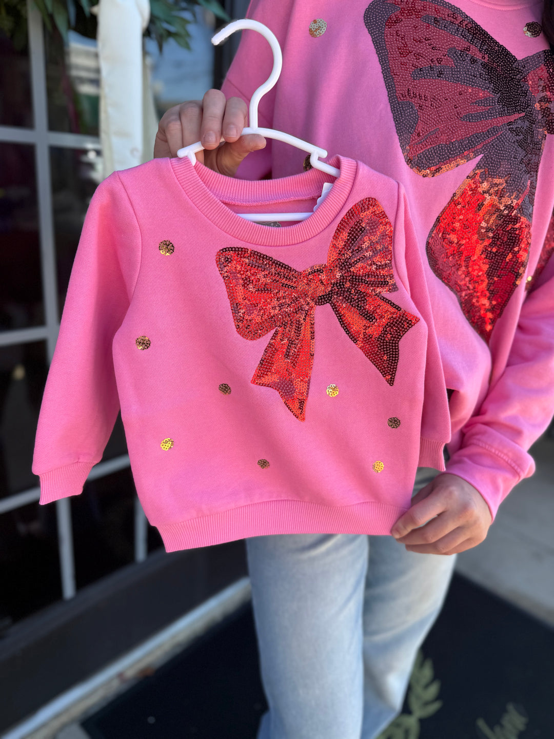 Pink Sequin Bow Sweatshirt in long-sleeved French terry with a red sequin bow and scattered gold sequins. Available in multiple sizes.