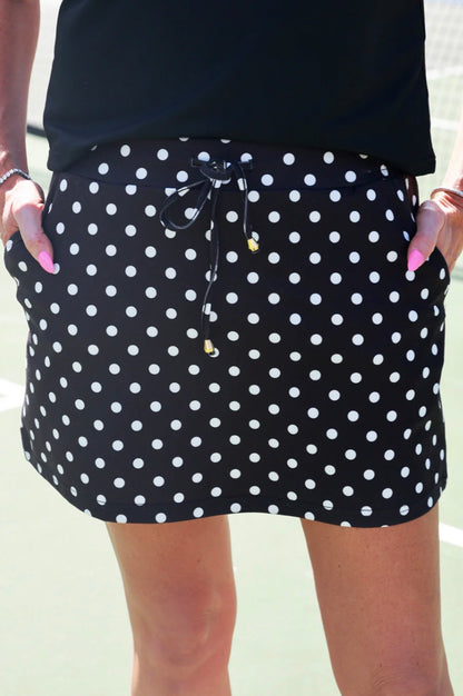 Dot Your Day Performance Skort—black with polka dots, drawstring waist, pockets. Available in sizes XS–XL.