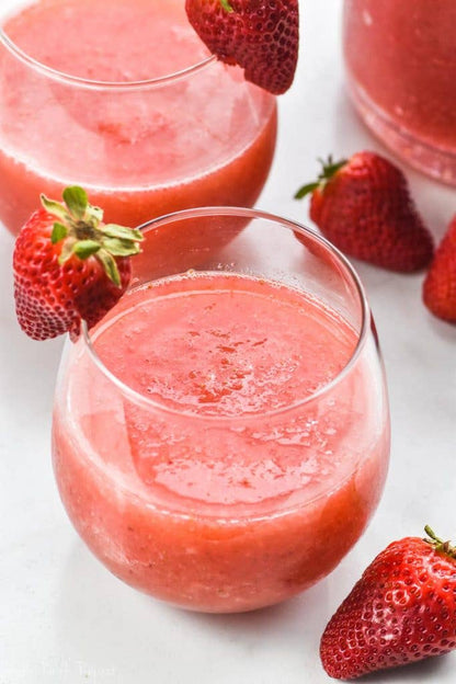 Two glasses of vivid pink strawberry smoothie with fresh strawberry garnish; available in 12 oz and 16 oz sizes.