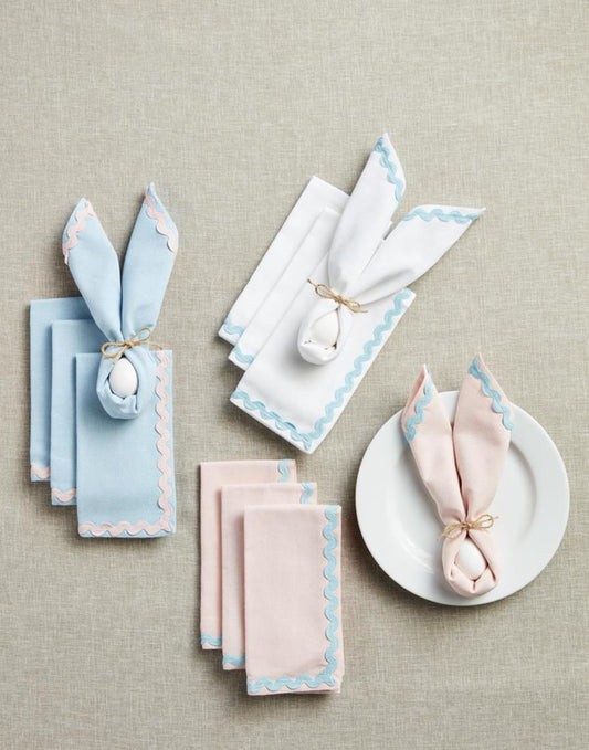 Pastel cotton napkins with ric rac trim, 18" x 18", folded into bunny-ear shapes.