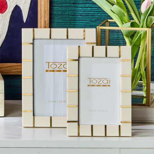 Two ivory and gold Brass Lines resin photo frames by Tozai Home, in two different sizes, displayed on a white surface.